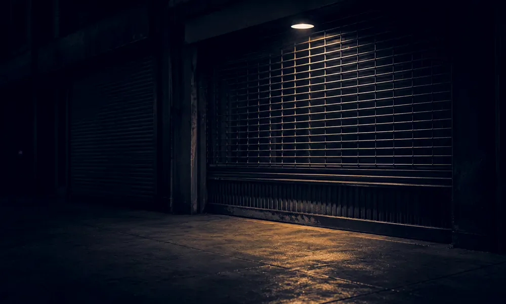 Metal storefront grate closed beneath an amber streetlight.
