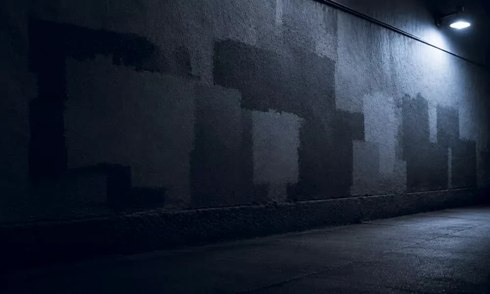 Fresh paint patches cover a wall beneath blue streetlight.