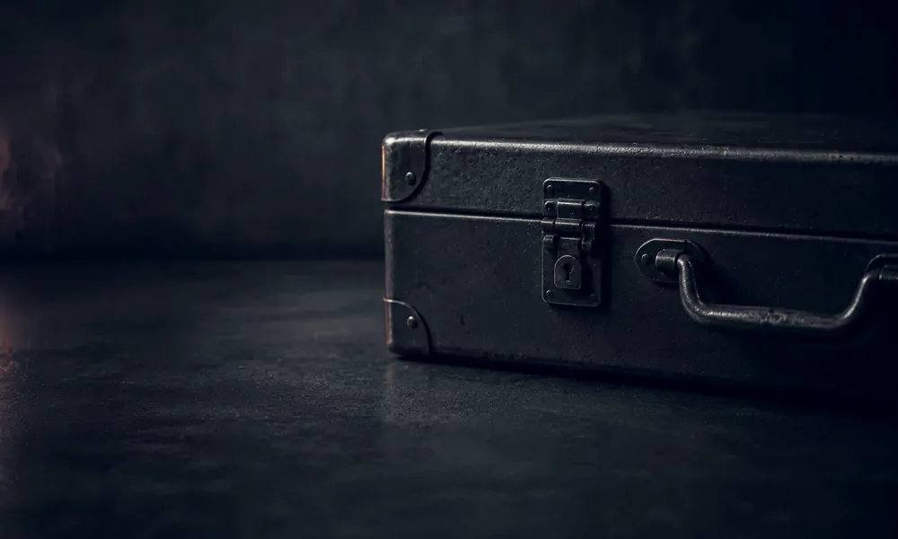 Closed metal case rests on a dark textured surface.