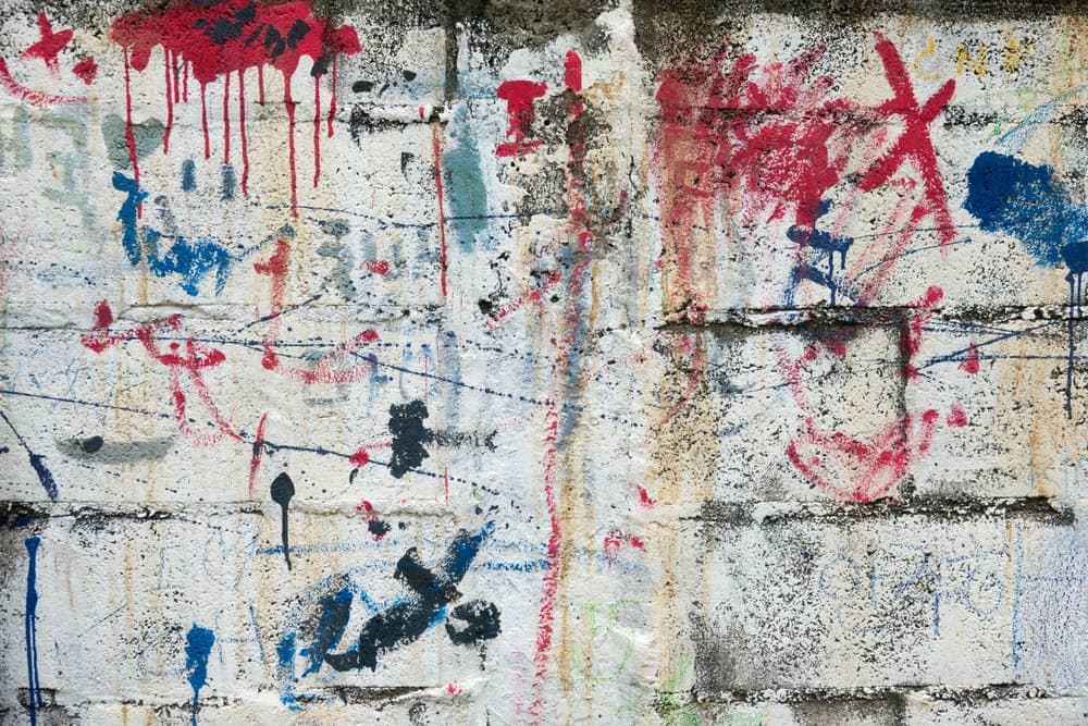 A wall covered in graffiti with red, blue, and white spray paint.