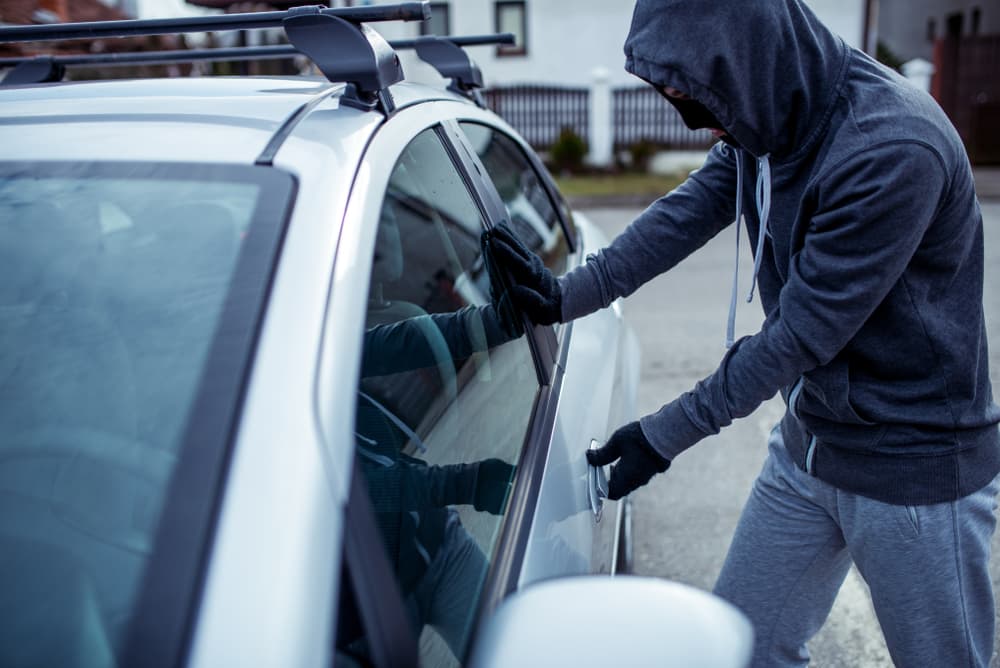 Person attempting to steal a car, symbolizing car theft.