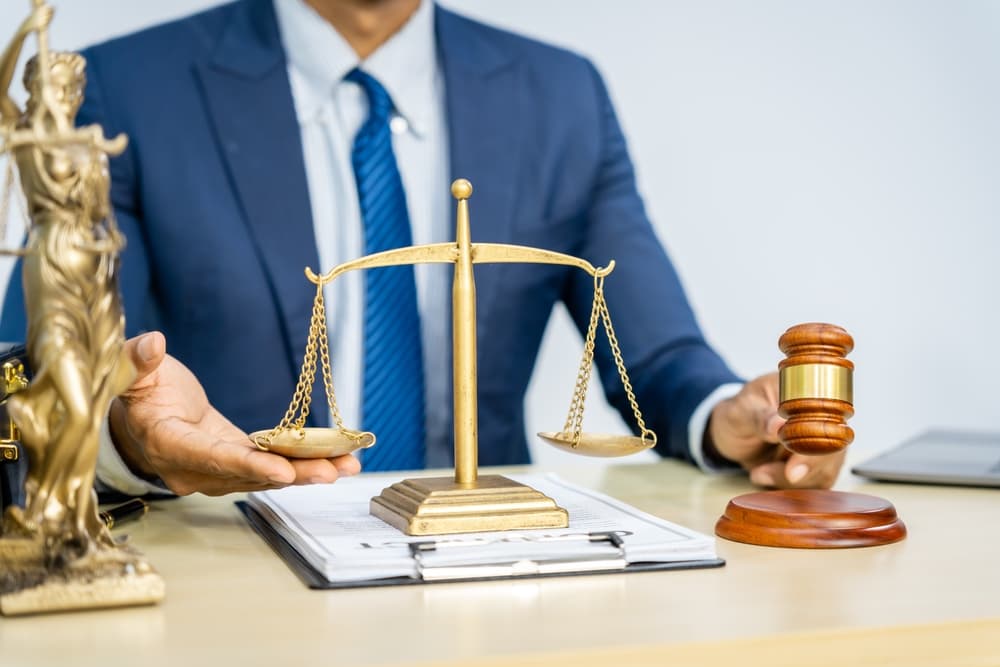 A male Asian lawyer in a formal suit reviewing contracts and legal documents, with a focus on constitutional and human rights in his legal practice